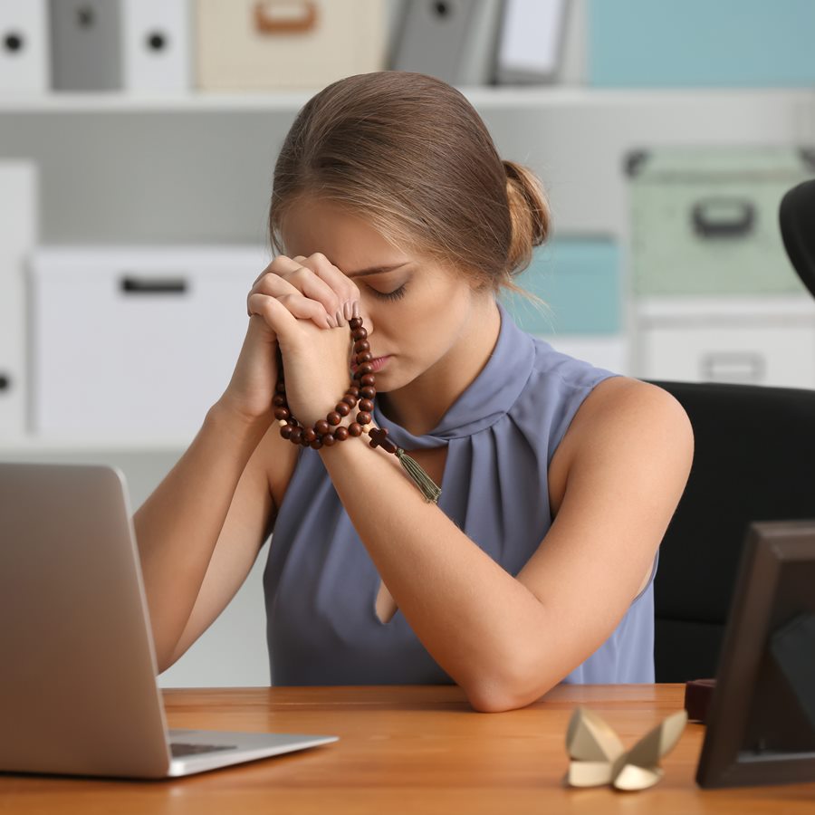 Beautiful young woman praying in office