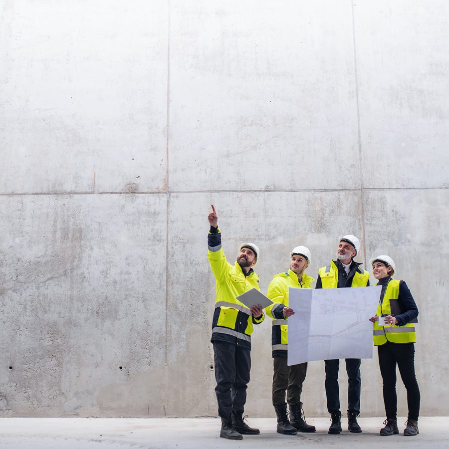 A group of engineers standing against concrete wall on construction site.